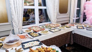 A buffet table with various dishes, a chandelier, and curtains.