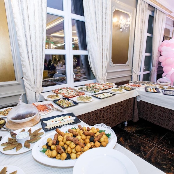 A buffet table with various dishes, a chandelier, and curtains.