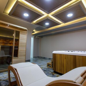 Un cuarto de spa con una mesa de masaje de madera, una bañera de hidromasaje y suelo de baldosas.