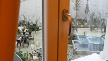 A view through a window of a patio area with outdoor furniture and a hot tub.