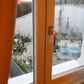 A view through a window of a patio area with outdoor furniture and a hot tub. - Elite Palace (Tirane)