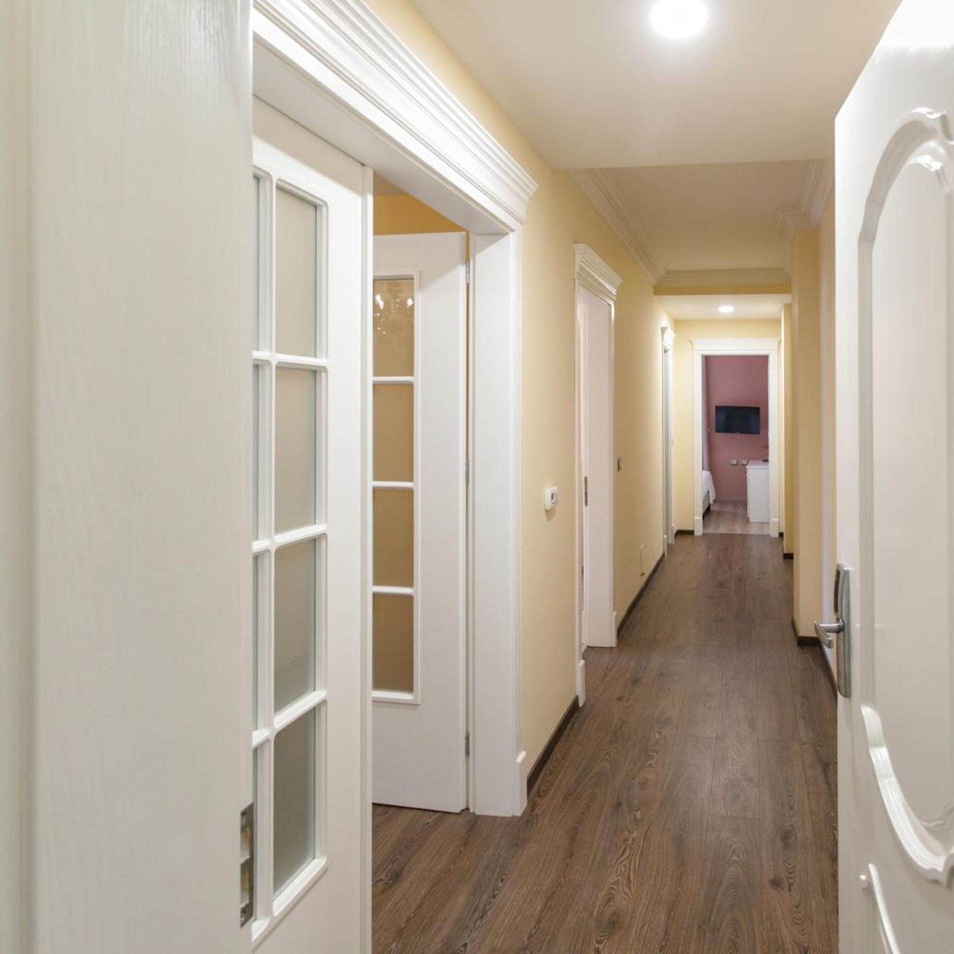 A hallway with wooden flooring and white doors.