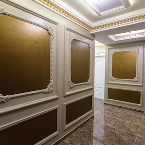 A corridor with ornate wall panels and a polished marble floor.