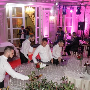 A room with tables set for a formal event, surrounded by guests.