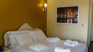 A hotel room with a large bed, a painting on the wall, and a nightstand with a lamp.