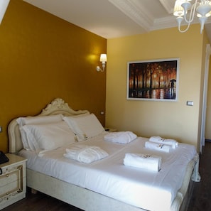 Quarto de hotel com uma cama grande, um quadro na parede e uma mesa de cabeceira com abajur.