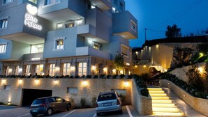 A multi-story hotel with a modern design, featuring balconies and a well-lit entrance.