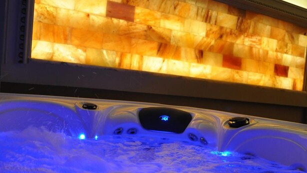 A hot tub with a digital control panel and a wooden panel above it.