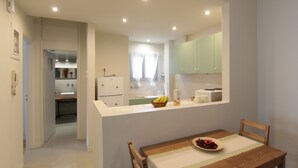Una cocina moderna con armarios blancos, una mesa de comedor con un mantel individual y vistas al baño contiguo.