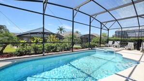 Una piscina con agua cristalina azul, rodeada por una zona cubierta con estructura metálica y techo de vidrio.