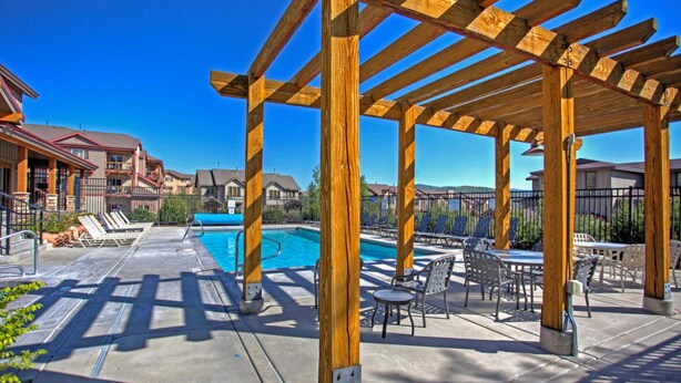 Eine Holzpergola über einem Pool mit Liegestühlen und Tischen.