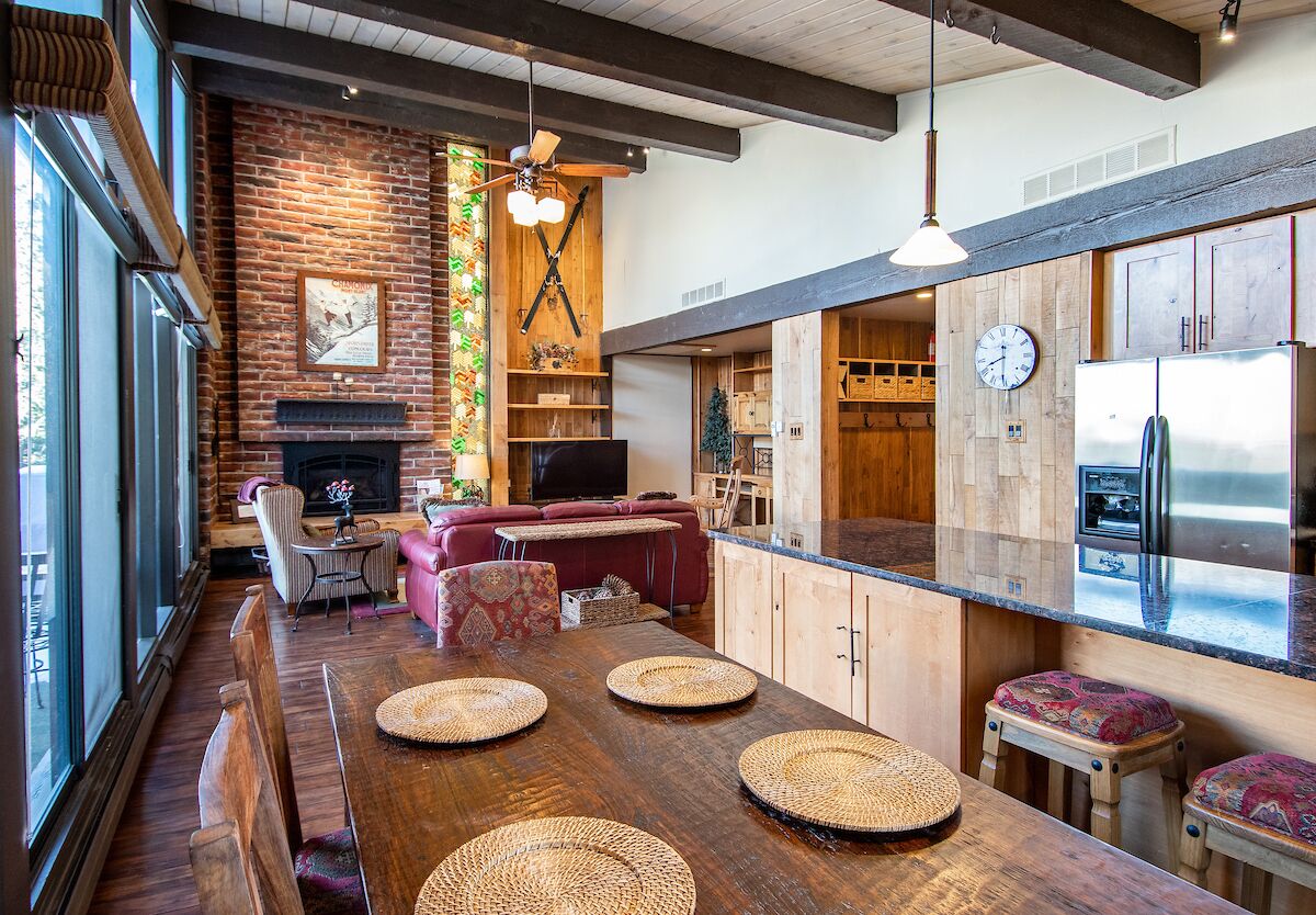 A modern kitchen with a wooden island, built-in appliances, and a large window overlooking the dining area.