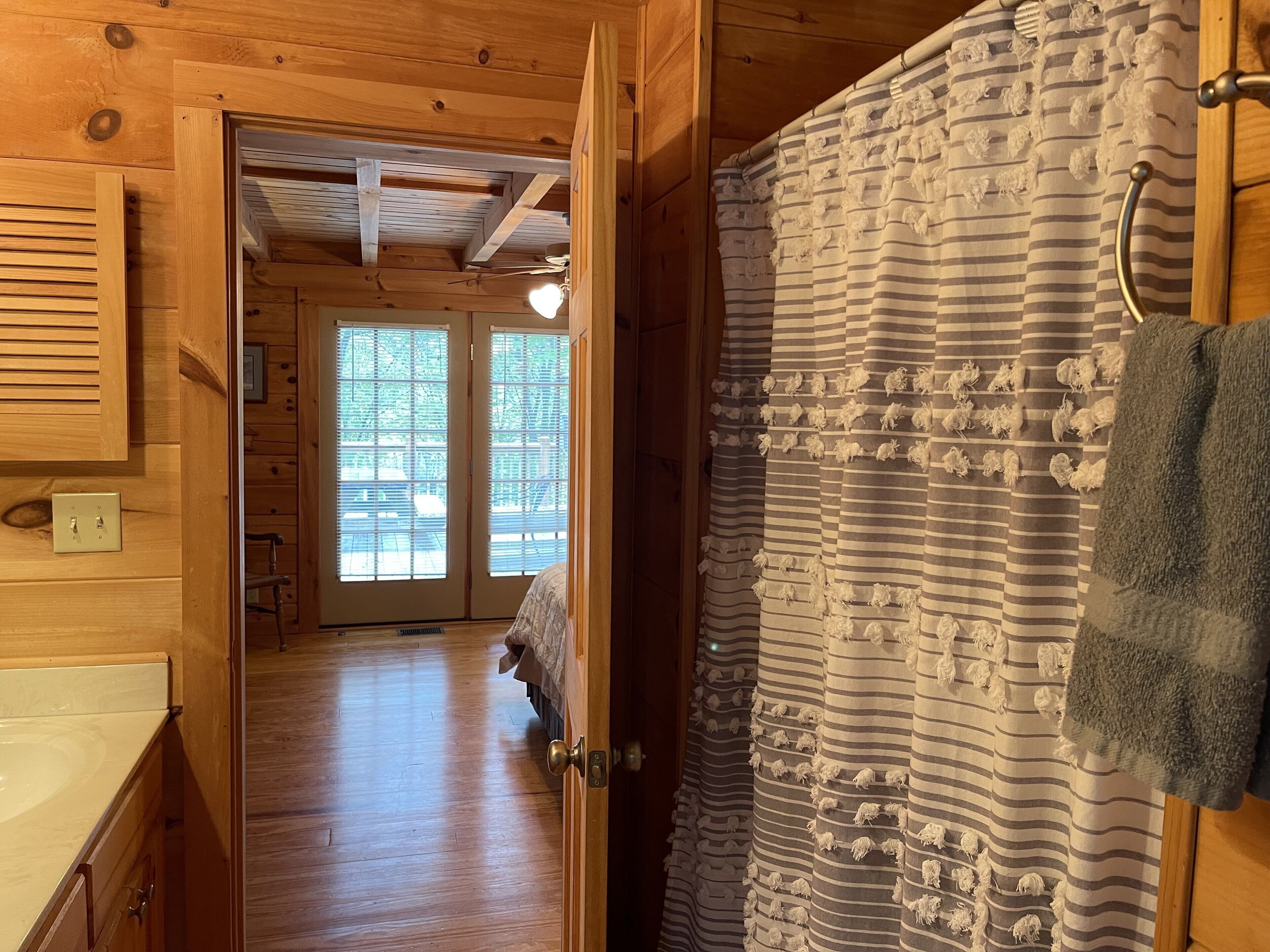 Un intérieur en bois avec une salle de bain dotée de rideaux à rayures et d’un porte-serviettes.