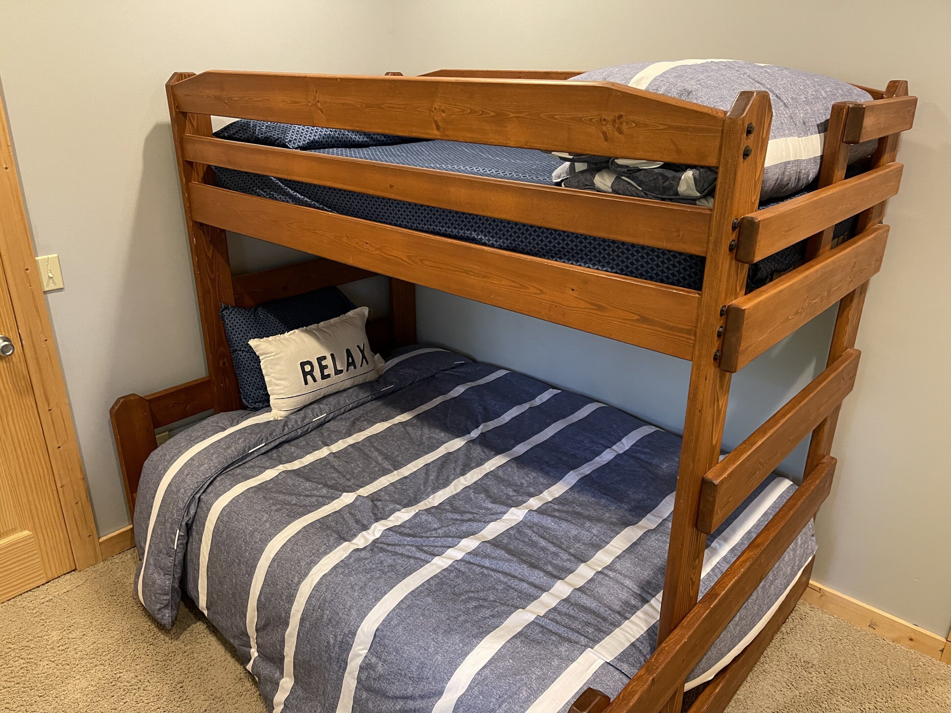 Ein Stockbett mit einer gestreiften Bettdecke und einem Kopfkissen mit dem Schriftzug "RELAX".