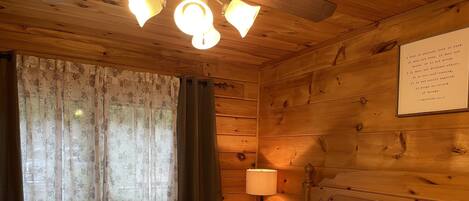 A wooden room with a bed, a nightstand, a lamp, and a wall with a quote.