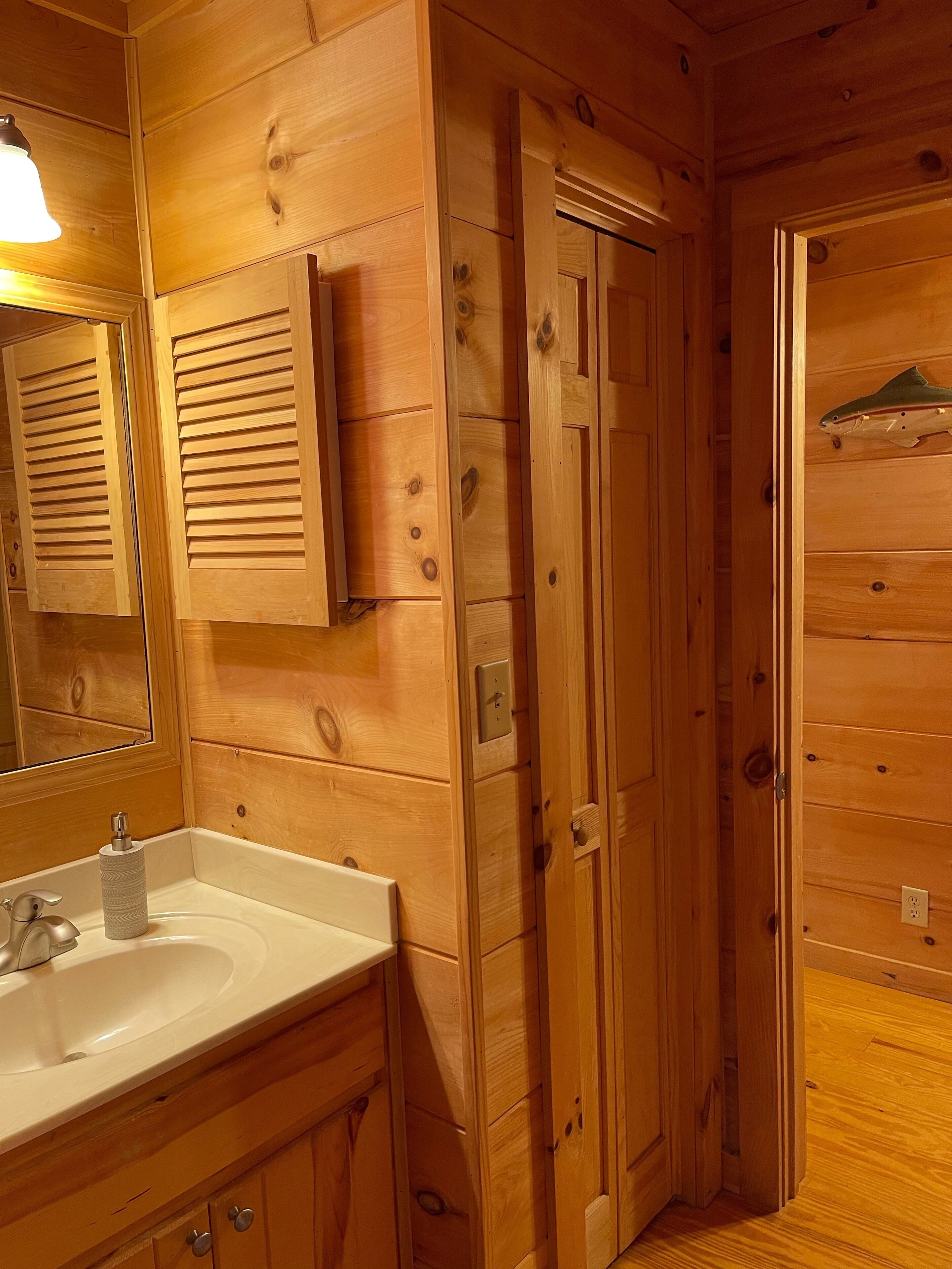 Une salle de bain en bois avec un lavabo, un miroir et des armoires en bois.
