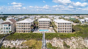 Un hotel costero con piscina central, varios balcones y acceso a la playa.