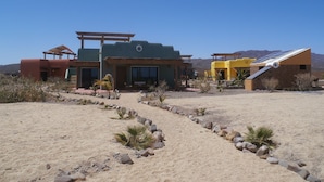 Un bâtiment de style désertique comprenant plusieurs pièces, un patio couvert et un panneau solaire.
