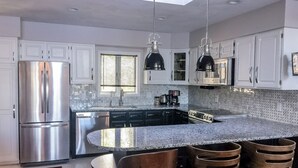 A modern kitchen with a central island, stainless steel appliances, and pendant lighting. - Amazing Lake House With All Amenities (Remsen)