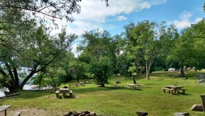 Ein Park mit Picknicktischen, einer Feuerstelle und einem Wanderweg.