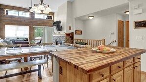 Une cuisine spacieuse dotée d’un grand îlot central, de meubles en bois et d’une cheminée en pierre.