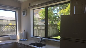 A kitchen with a window, a sink, a toaster, and a refrigerator. - Cozy two story hideaway (Whangamata)