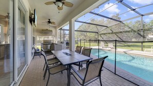 A covered outdoor area with a pool, patio furniture, and a grill.