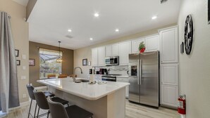 A modern kitchen with white cabinets, stainless steel appliances, and a central island with bar stools.