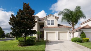 A two-story house with a garage, surrounded by well-maintained lawns and trees.