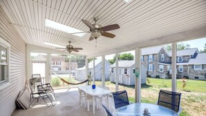 A covered patio with a table and chairs, ceiling fans, and a view of neighboring houses. - Albion by Seaside Vacations & Sales (Chincoteague Island)