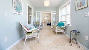 A hallway with wicker chairs, a small table, and artwork on the walls. - Albion by Seaside Vacations & Sales (Chincoteague Island)