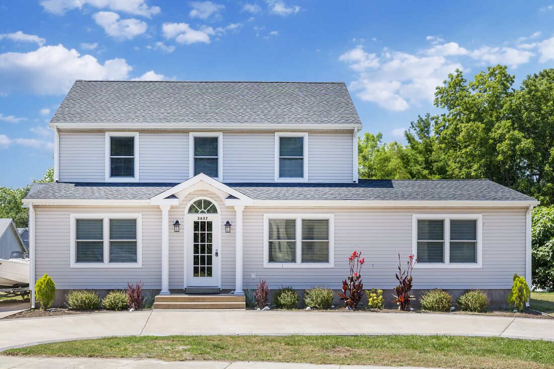 A two-story house with a front entrance, a garage, and a well-maintained lawn.