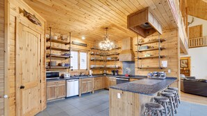 Une cuisine spacieuse avec des meubles en bois, un îlot central doté de tabourets et un lustre.