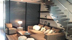 A modern living room with a sectional sofa, a coffee table, and a lamp. There is a staircase with glass railings and a railing. - beautiful townhouse on Brickell Miami´s prestigious residential are, free wifi (Miami)