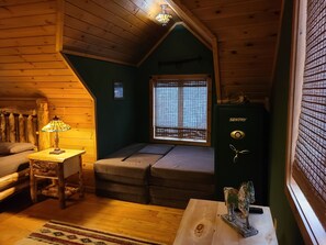 Cozy cabin-style room with a sloped ceiling, sofa, table, and lamp.