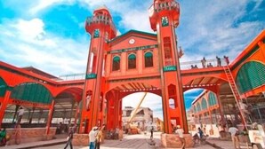 Une arche rouge surmontée d’une horloge et d’une enseigne.