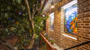 A brick-walled corridor with hanging plants and a Buddha painting. - Gurung's Home (Kathmandu)