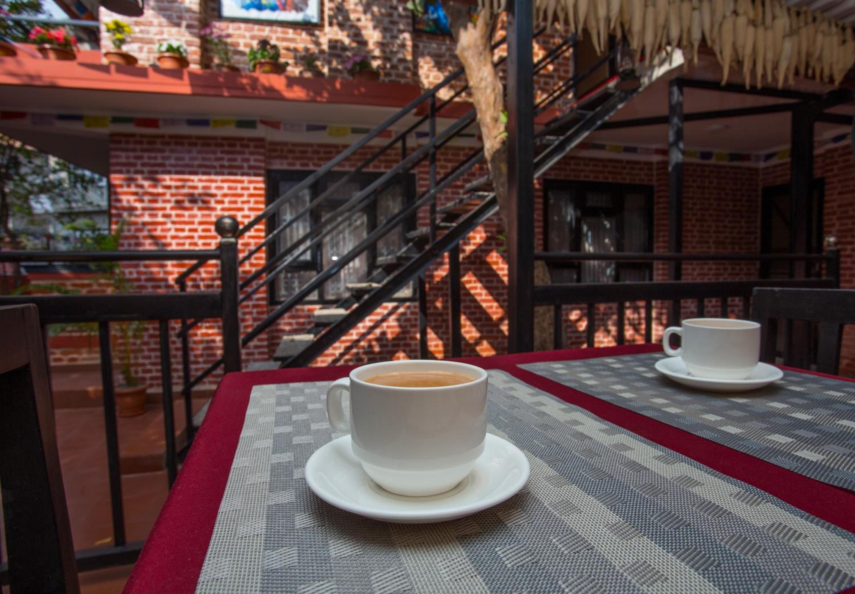 Una taza de café y su platillo sobre una mesa con mantel estampado.