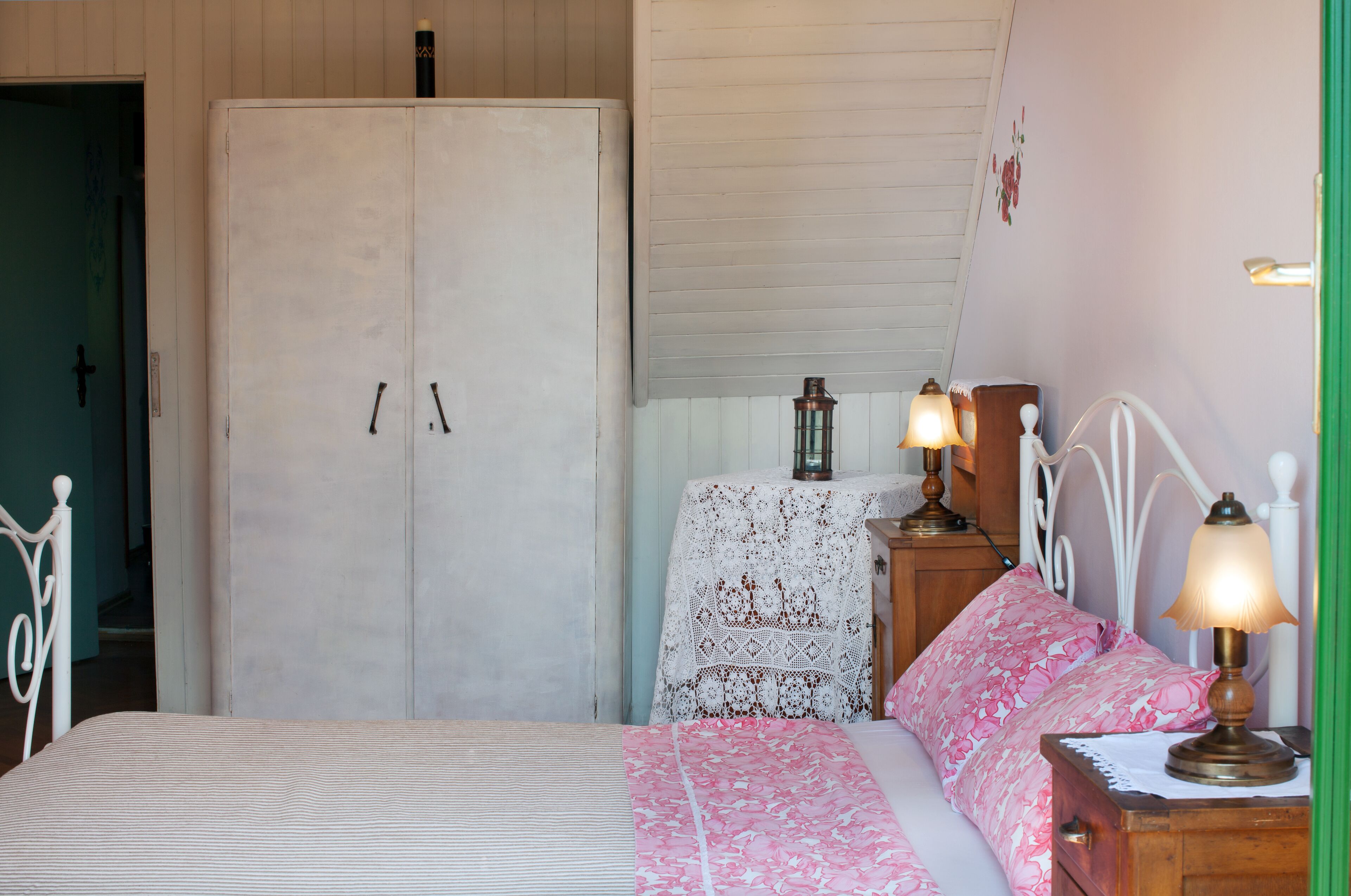 Un dormitorio con cama, armario, mesita de noche con lámpara y un adorno en la pared.