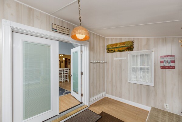 A hallway with a wooden floor, a glass door, a hanging light fixture, and a sign on the wall.