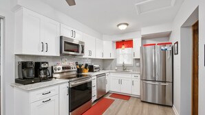 Una cocina moderna con gabinetes blancos, electrodomésticos de acero inoxidable y una pared de acento roja.