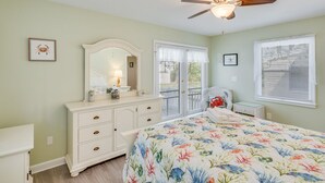 Un dormitorio con cama, cómoda y ventilador de techo.