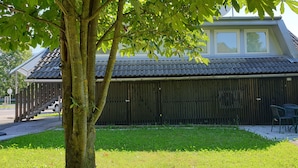 Ein Gebäude mit einem Ziegeldach, einem Holzzaun und einem Baum im Vordergrund.
