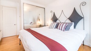 A bedroom with a large bed, a wardrobe, and a mirror. - River View, Penthouse Apartment, Zone 2, Hammersmith, London, 2 Bedrooms  2 Bath (London)