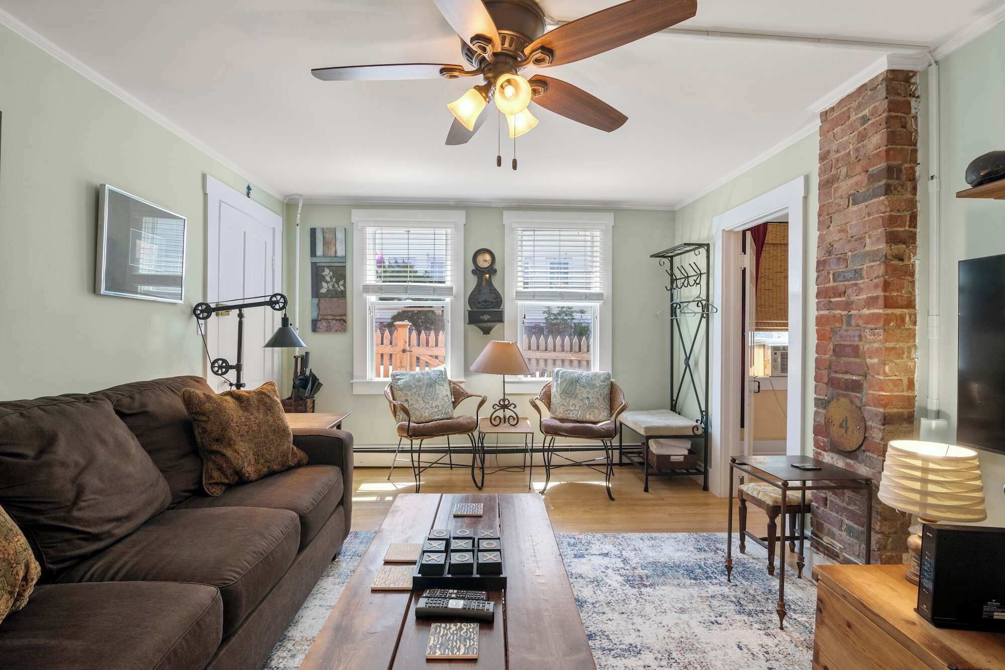 A living room with a sofa, chairs, a coffee table, a fireplace, and a ceiling fan.