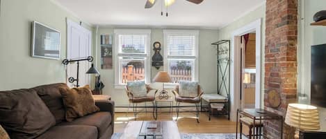 A living room with a sofa, chairs, a coffee table, a fireplace, and a ceiling fan.
