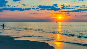 A sunset over a calm sea with a person walking on the beach. - Steps to Commercial St Walk to Beach! (Provincetown)