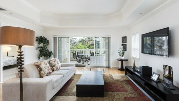A modern living room with a white sofa, a black coffee table, and a large window offering a view of the outdoors. - Modern and Spacious 3-Suite Apartment (Kissimmee)