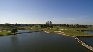 A golf course with a large body of water, a bridge, and a distant building. - Modern and Spacious 3-Suite Apartment (Kissimmee)