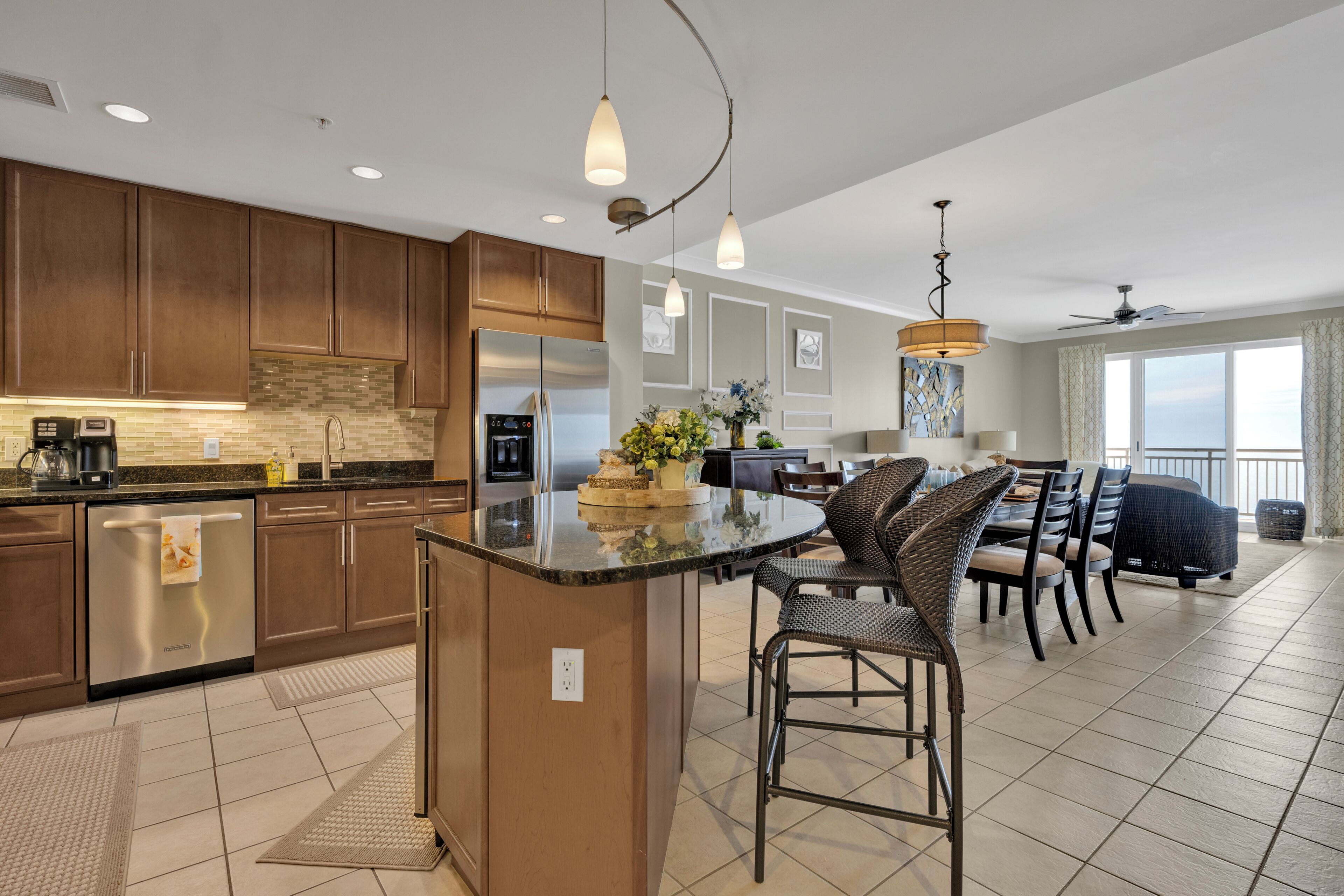 A modern kitchen with a central island, dark wooden cabinets, stainless steel appliances, and pendant lighting.